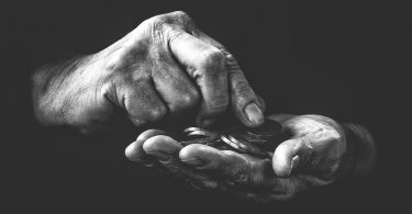 O que é fundo de combate à pobreza - Imagem preto e branco com as mãos de uma pessoa contando moedas