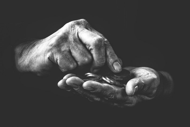 O que é fundo de combate à pobreza - Imagem preto e branco com as mãos de uma pessoa contando moedas