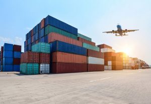 Entenda a diferença entre CTe e MDFe - Pátio de um terminal de transporte com vários containers empilhados e um avião sobrevoando